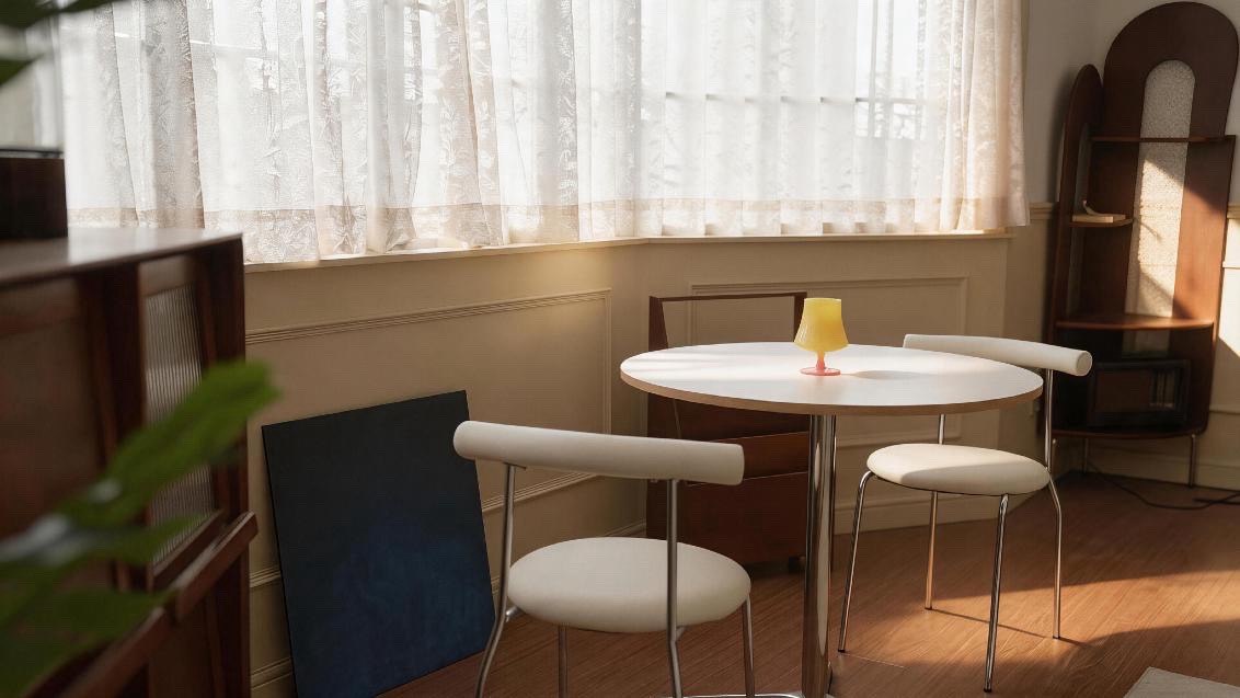 Studio dining room: round table, sheer curtains, wood-panelled wall